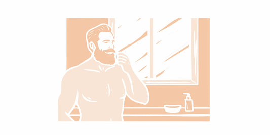 Man applying beard balm to a well-groomed beard in a bathroom with natural lighting
