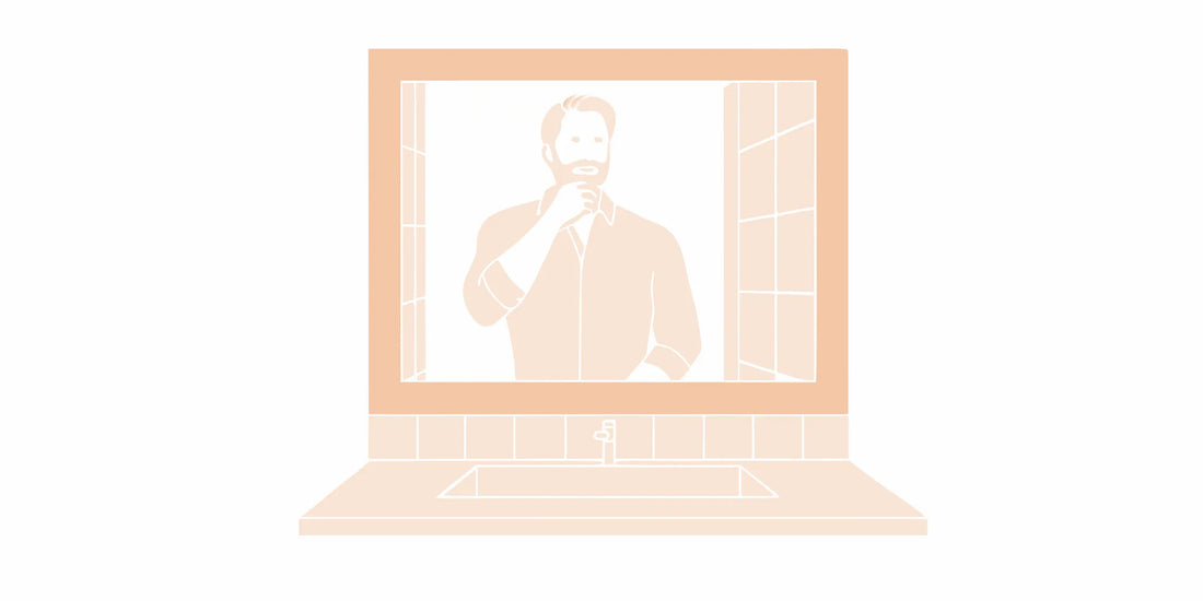 Man examining his beard in the mirror to start a new beard care routine.